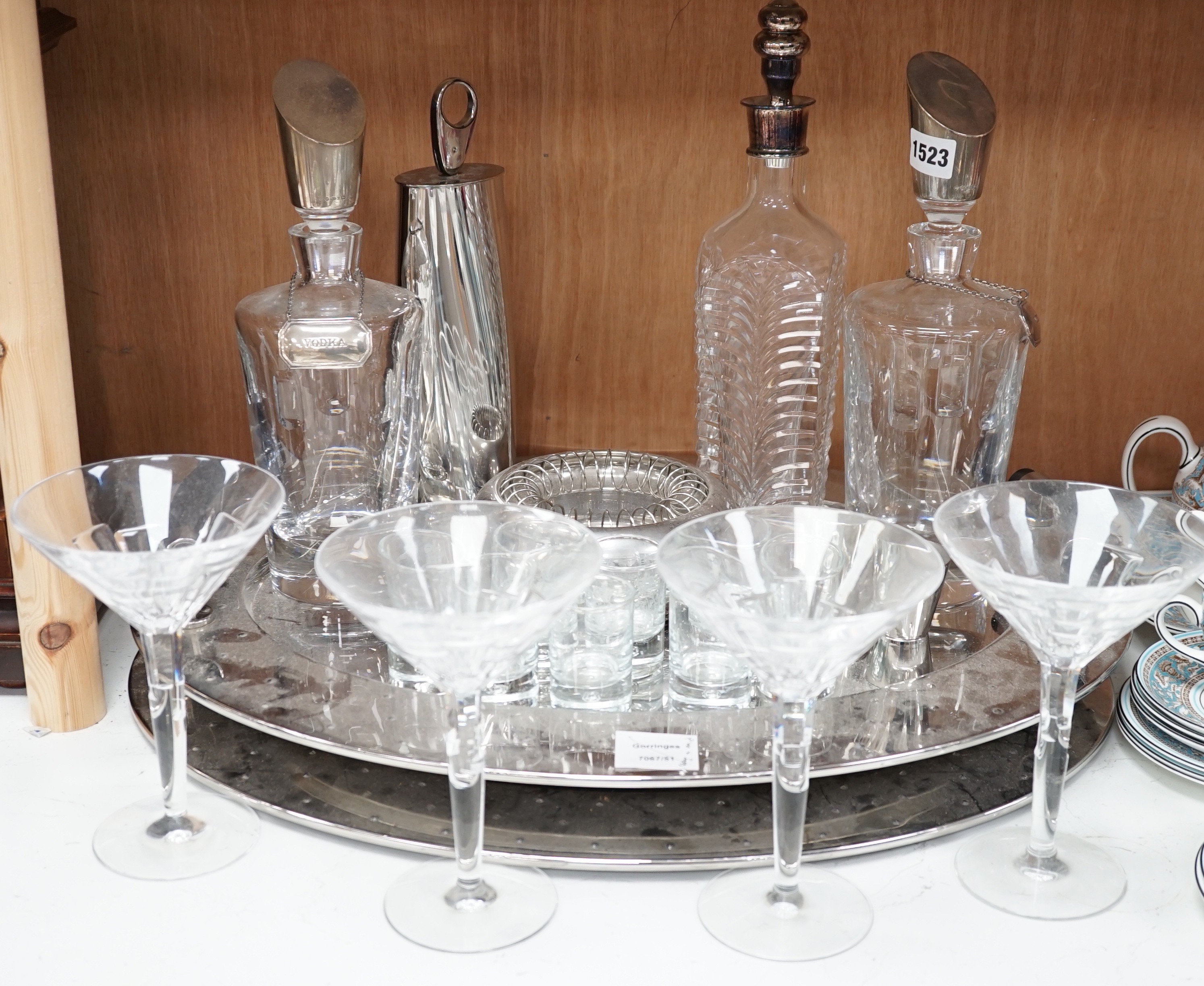 A stylish oval chromed metal two handled tray, with assorted decanters, glassware and cocktail equipment, 56 cms wide